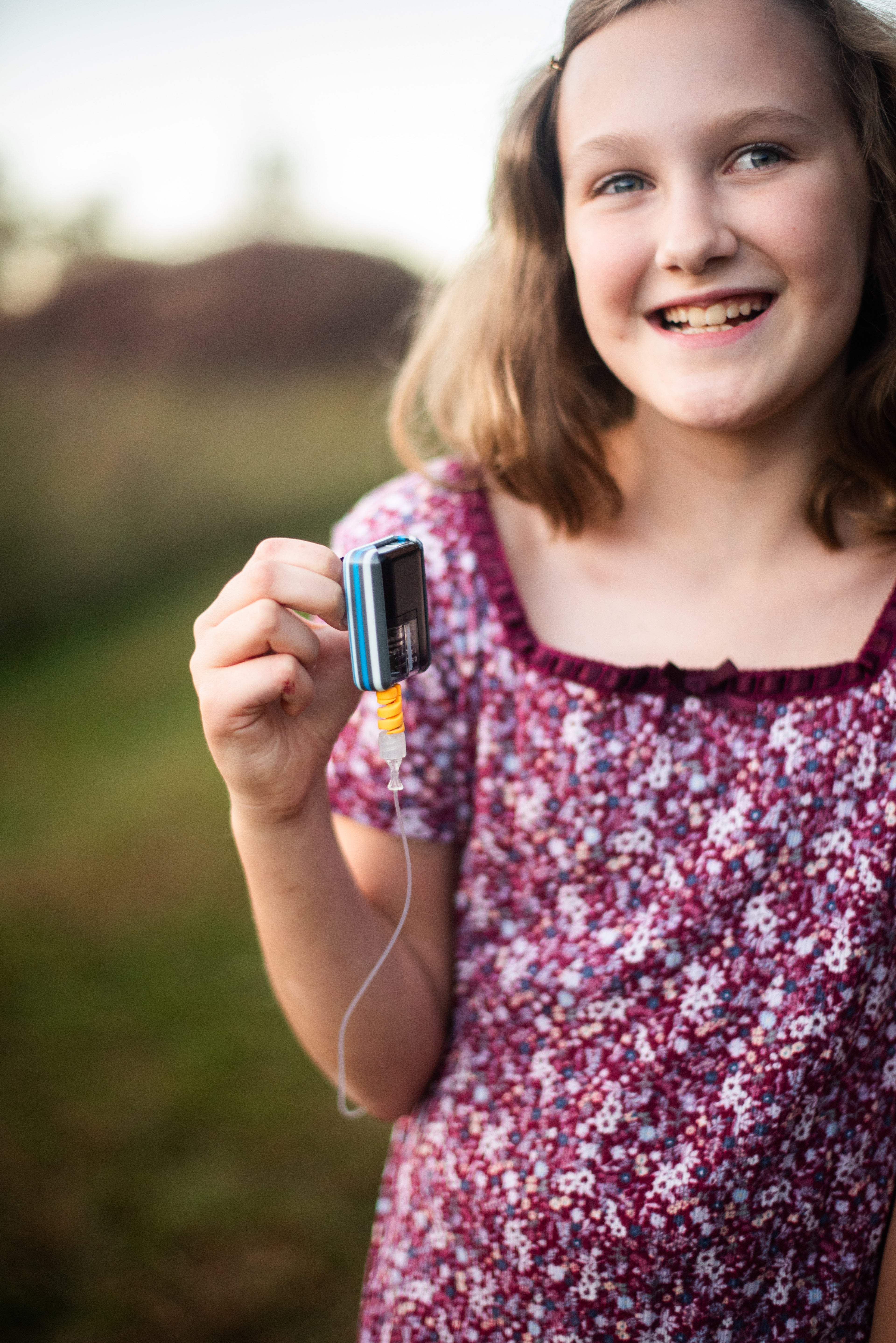 Young Girl holding a customer striped Tanem Mobi™ diabetes insulin pump case.